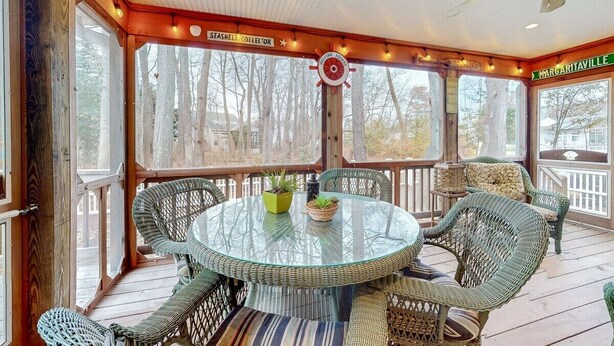 A covered outdoor deck with wicker furniture, a glass table, and a view of trees. - Free Daily Activities, Bikes,Grill, Pool&Tennis, BHChairs, 5 MINUTES from Beach! (Ocean View)