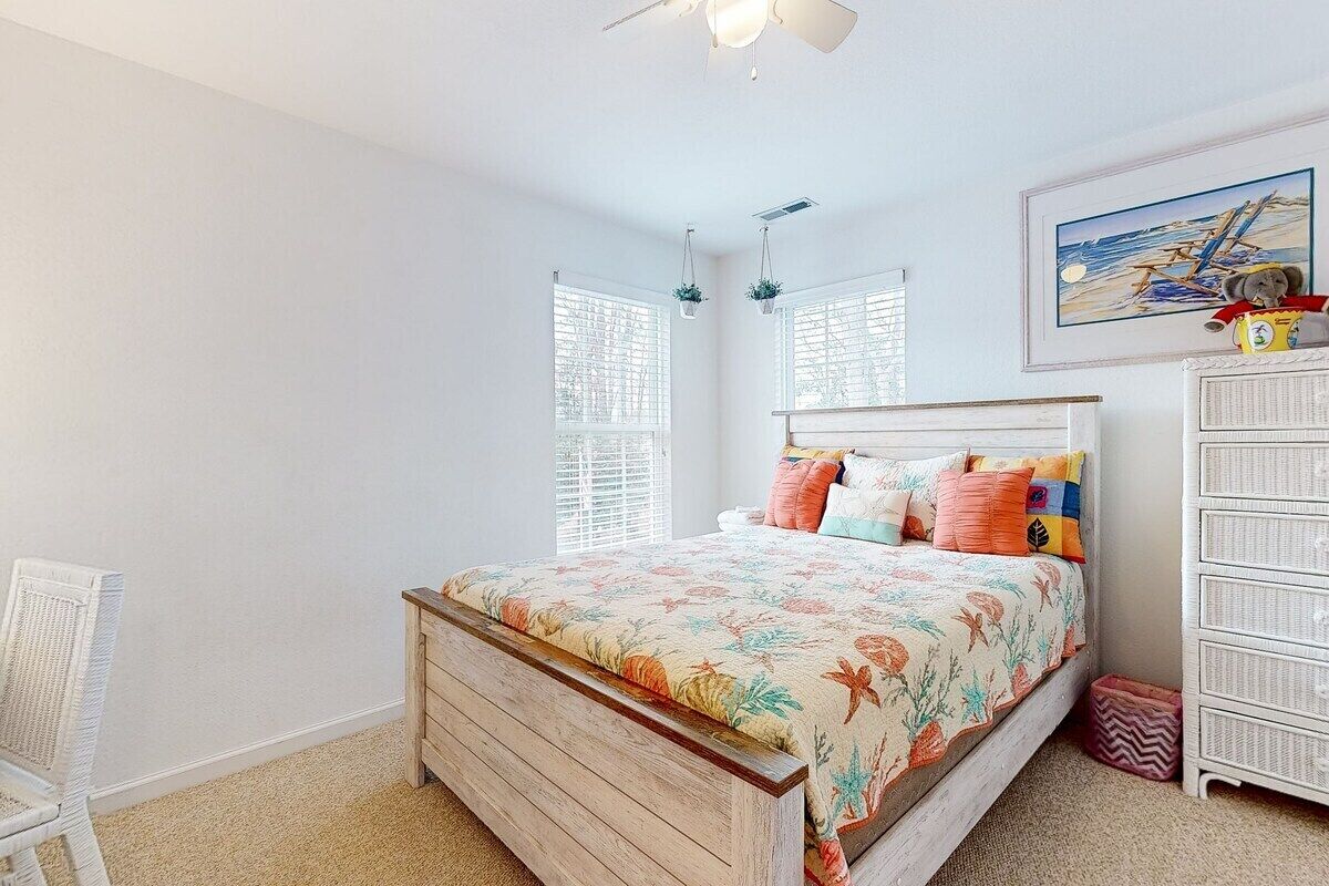 A bedroom with a wooden bed, white walls, a ceiling fan, and a window with blinds.
