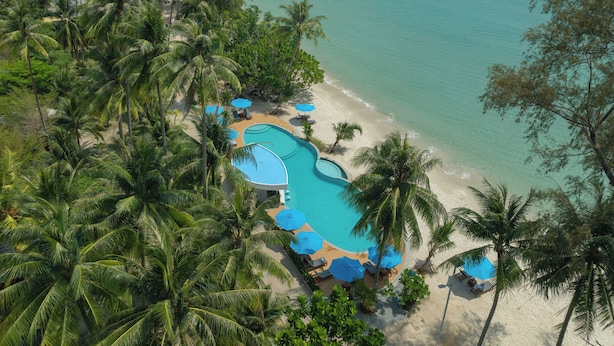 Un resort con piscina, playa y palmeras.