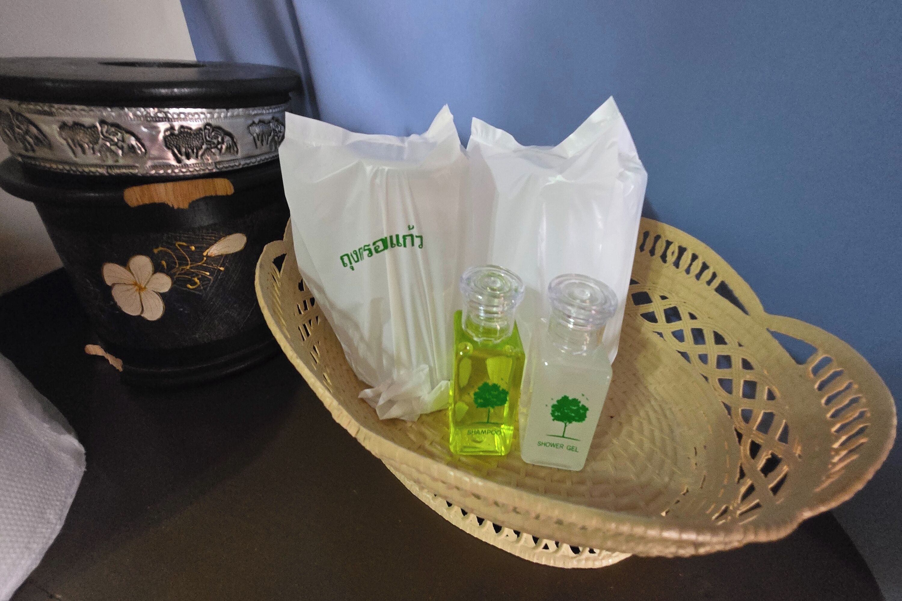 En bakke med to shampoo- og brusegelflasker, en hvid plastpose og en dekorativ sort beholder.