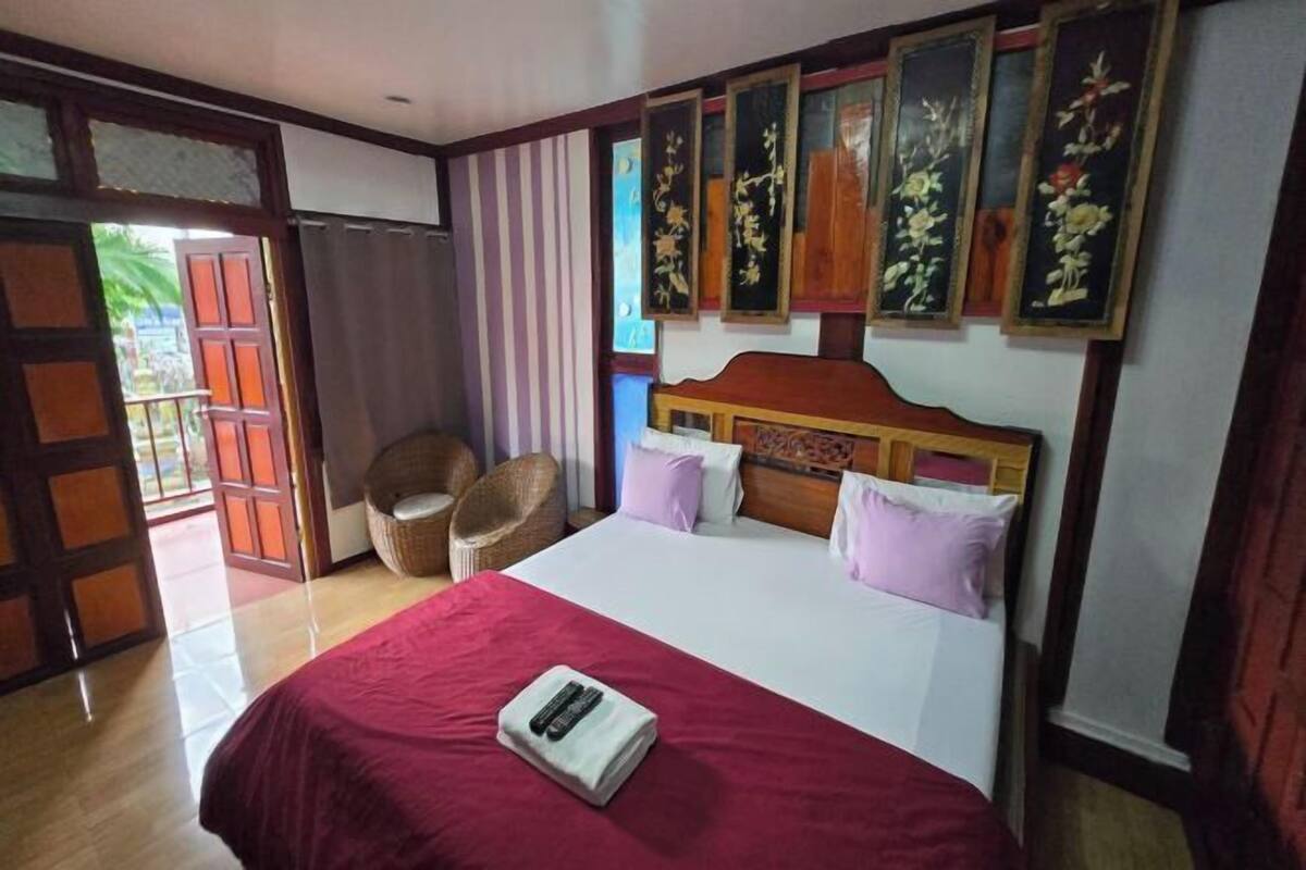 A hotel room with a bed, a chair, and a door leading to an outdoor area.