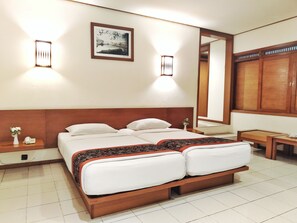 A hotel room with a large bed, two bedside tables, a nightstand, a mirror, and a framed picture on the wall. - The Cipaku Garden Hotel (Bandung)