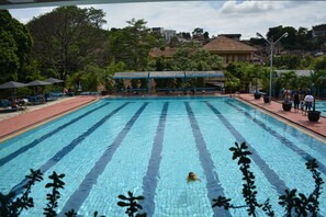 Une piscine dotée d’une terrasse carrelée, de bancs et de parasols.