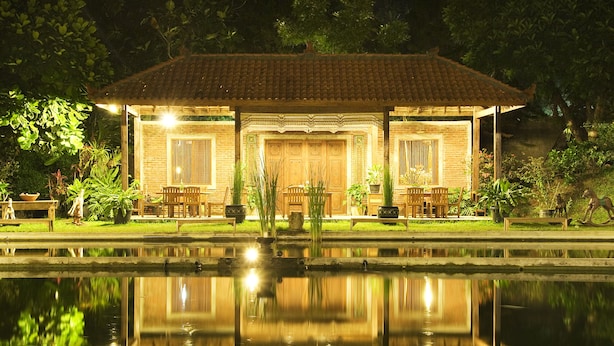 Een traditioneel gebouw met een pannendak, een houten veranda en een spiegeling in het water ervoor.