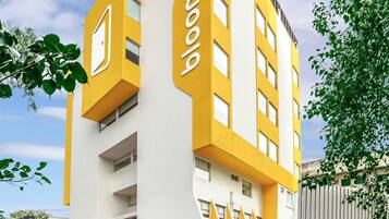 Un edificio moderno con una decoración en tonos amarillo y blanco, con el nombre 'bloomrooms' en la entrada.