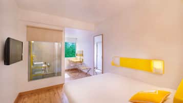 A modern hotel room with a large bed, a desk, and a bathroom.