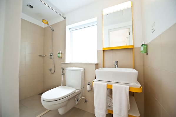 Un baño con inodoro, bidé, lavamanos y espejo.
