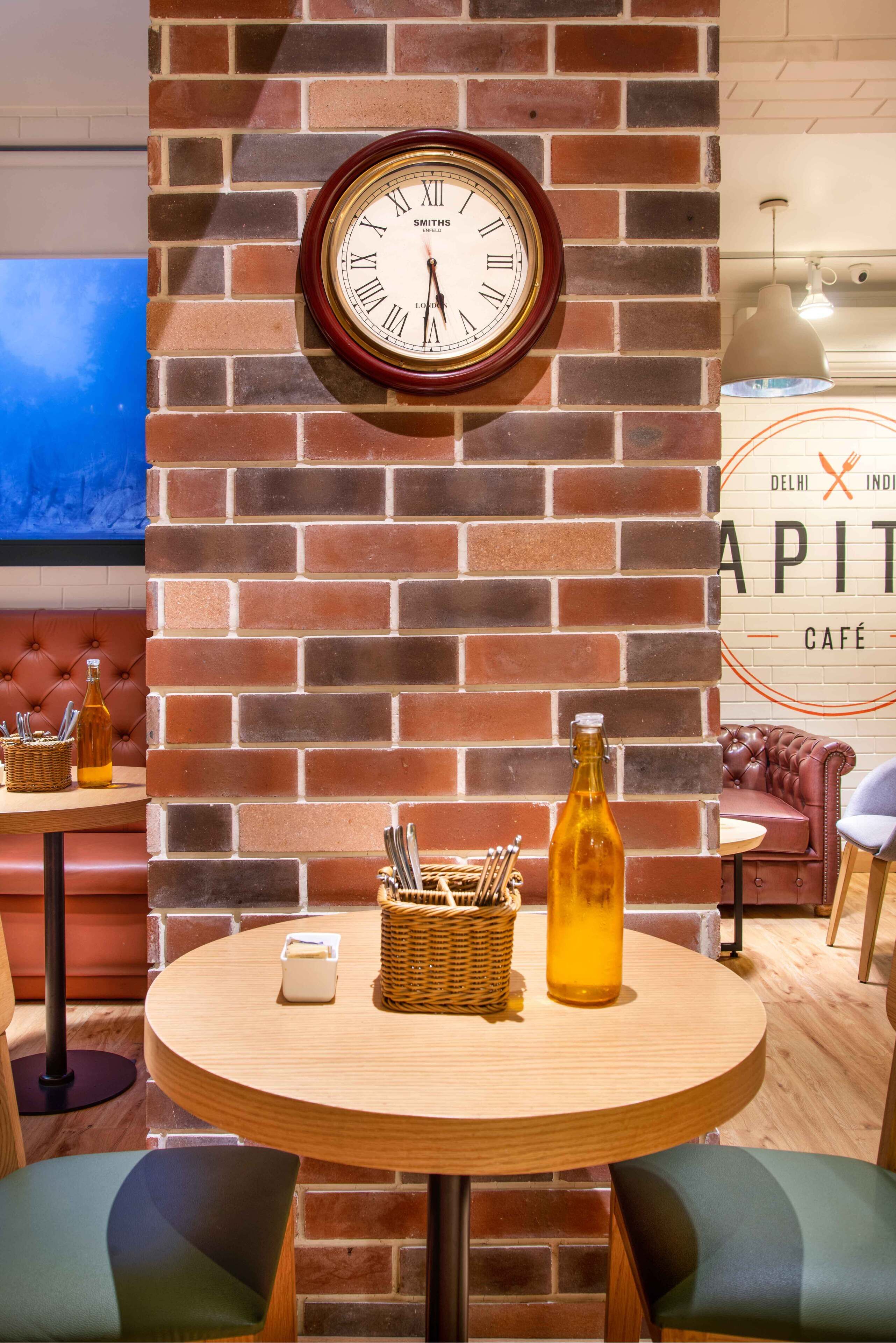 A brick wall with a clock, a table with a bottle, and a wicker basket.