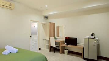 A hotel room with a bed, a desk, a television, a refrigerator, and a bathroom.