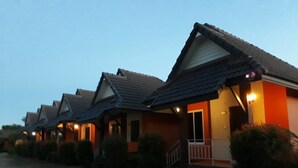 A row of single-story houses with pitched roofs and front porches, each with a small porch light. - Suansiri Resort (Mae Chan)
