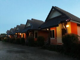 A row of single-story houses with pitched roofs and front porches, each with a small porch light.