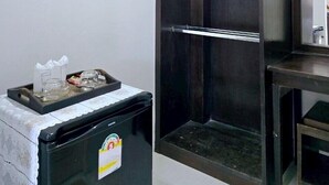 A compact room with a dark wooden wardrobe, a small table with a tissue box, and a trash bin. - Suansiri Resort (Mae Chan)
