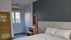 Un dormitorio con una cama grande, una mesita de noche de madera, un espejo y una puerta con un letrero.