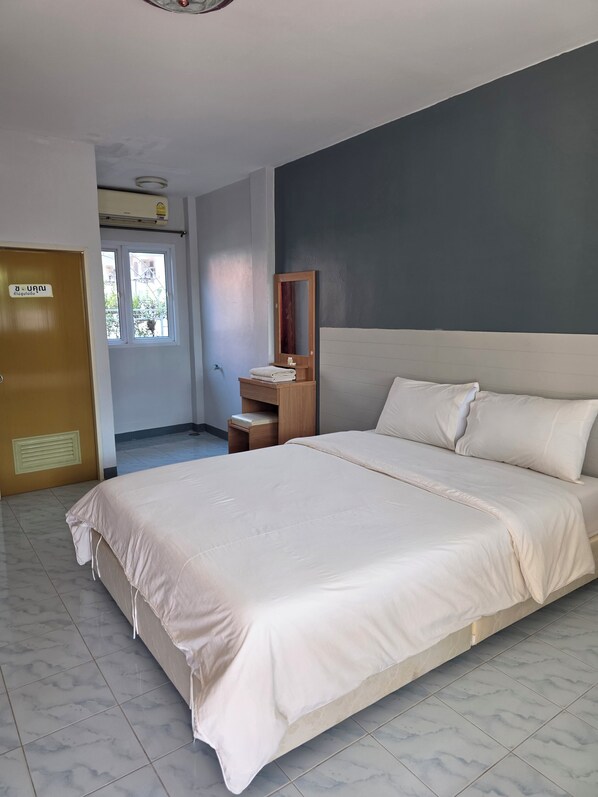 A bedroom with a large bed, a wooden nightstand, a mirror, and a door with a sign.
