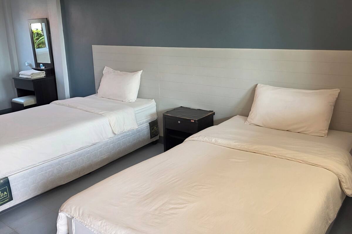 Ein Hotelzimmer mit zwei Betten, einem Nachttisch, einem Spiegel und einem kleinen Tisch.