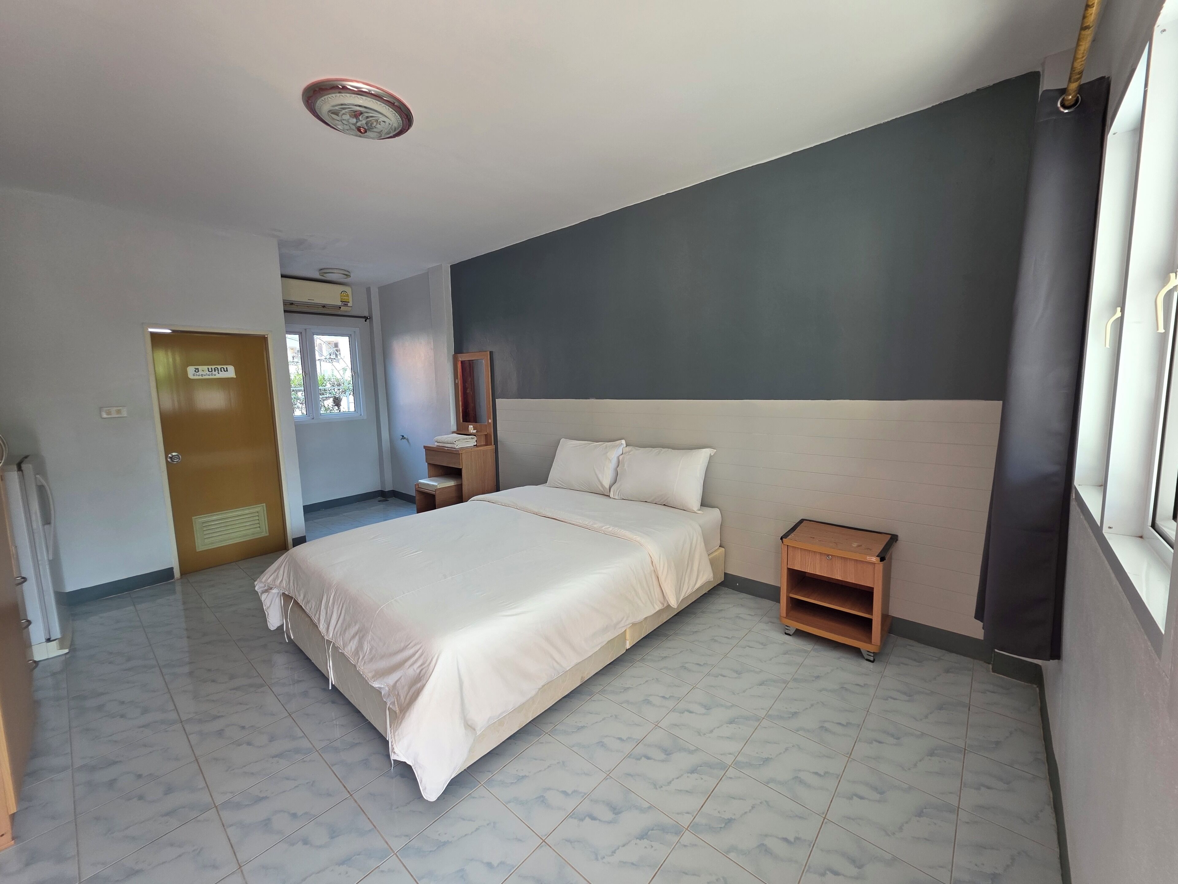 Una habitación de hotel con cama, mesita de noche y una pequeña mesilla de noche de madera.