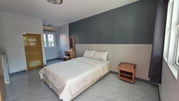 Una habitación de hotel con cama, mesita de noche y una pequeña mesilla de noche de madera.