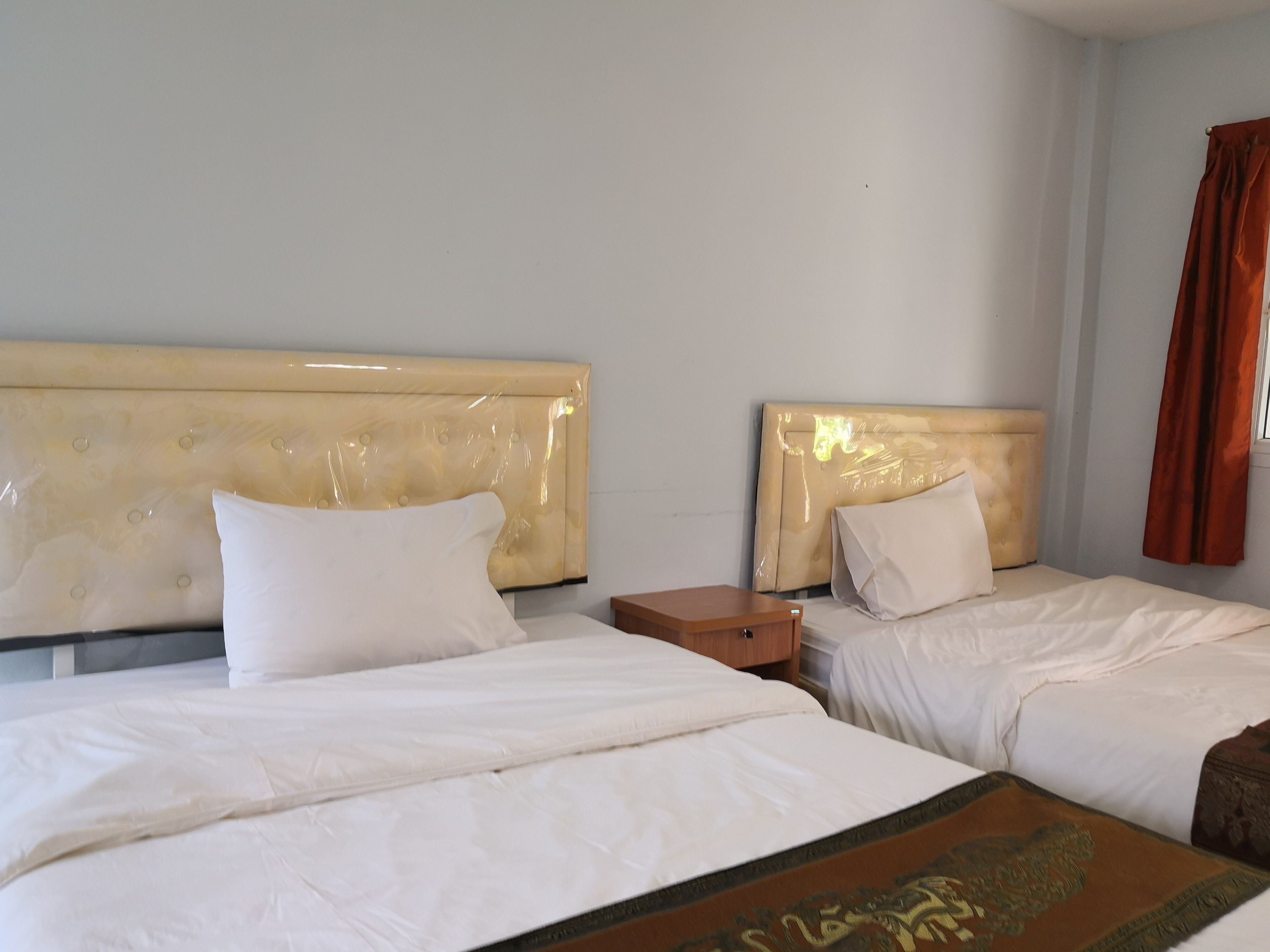 Habitació d'hotel amb dos llits, cadascun amb capçalera i roba de llit blanca. Hi ha una petita taula de nit de fusta entre els llits.