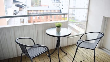A balcony with two chairs and a small table, overlooking a cityscape.
