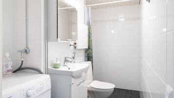 A modern bathroom with a built-in washer and dryer, a sink, and a toilet.