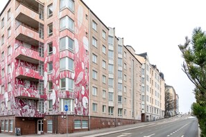 A multi-story building with a distinctive red and white floral facade, multiple balconies, and a clear street view. - Hiisi Homes Helsinki Sörnäinen (Helsinki)