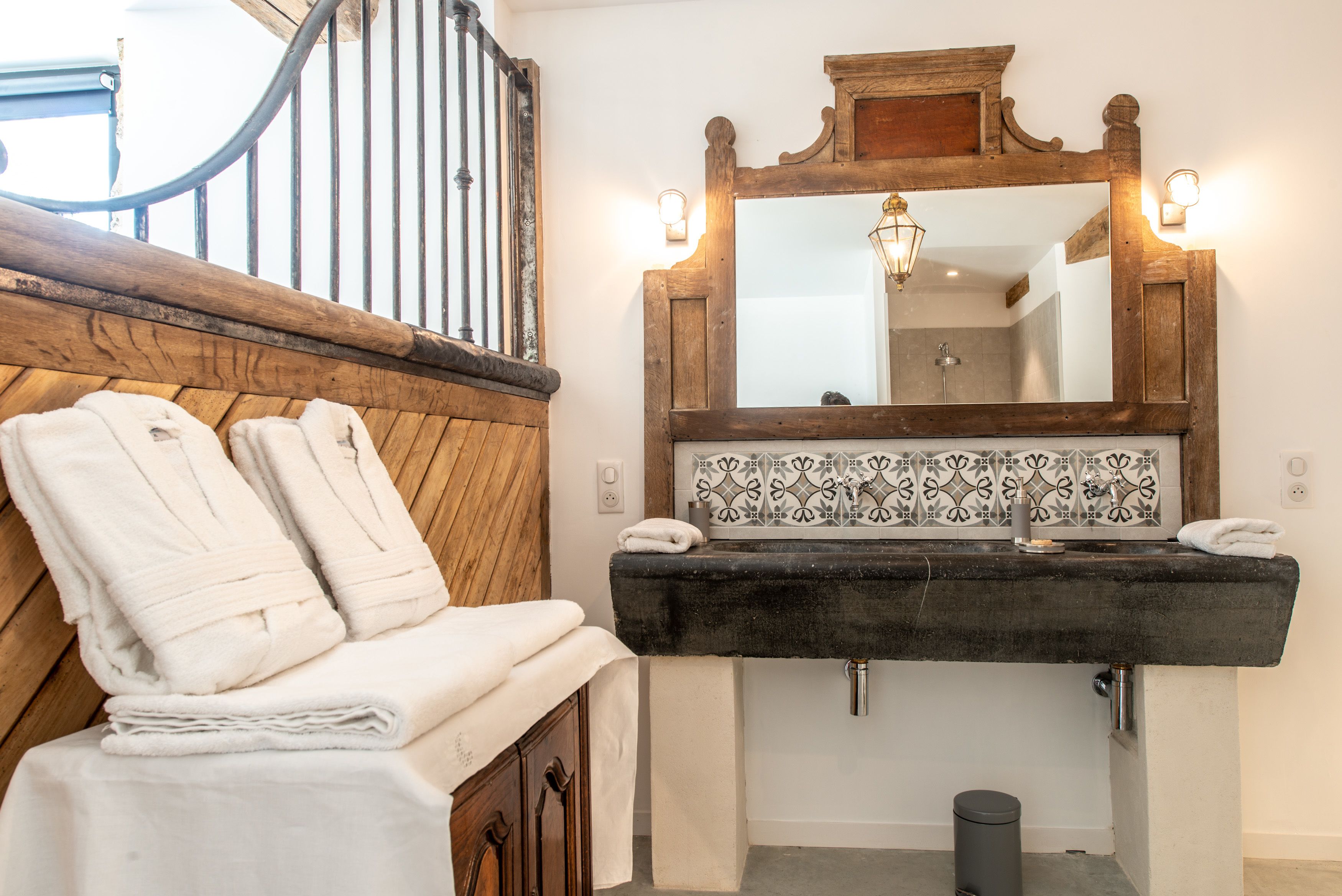 A bathroom with a wooden bench, a black sink, and a mirror with a wooden frame.
