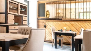 A modern dining area with a wooden wall, a clock, and a table with chairs. - L'Ecrin des Vignes (Sermiers)