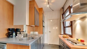 A modern kitchen with stainless steel appliances, wooden cabinets, and a granite countertop. - EUROPEA Residence Grande Place Brussels (Brussels)