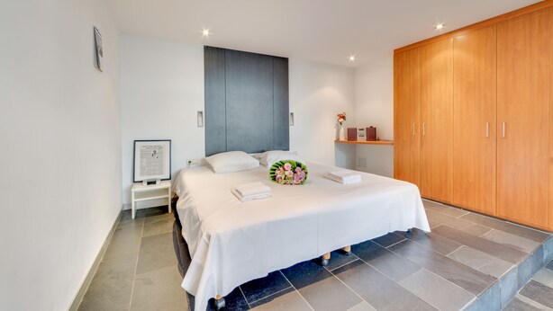 A modern bedroom with a large bed, a wooden wardrobe, and a small bedside table with a framed picture. - EUROPEA Residence Grande Place Brussels (Brussels)