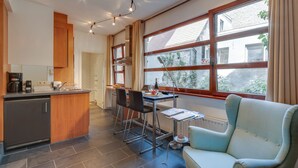 A modern kitchen with a dining area, a sofa, and a view of the outside. - EUROPEA Residence Grande Place Brussels (Brussels)