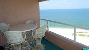 Ein Balkon mit Tisch und Stühlen mit Blick auf einen Strand und den Ozean.