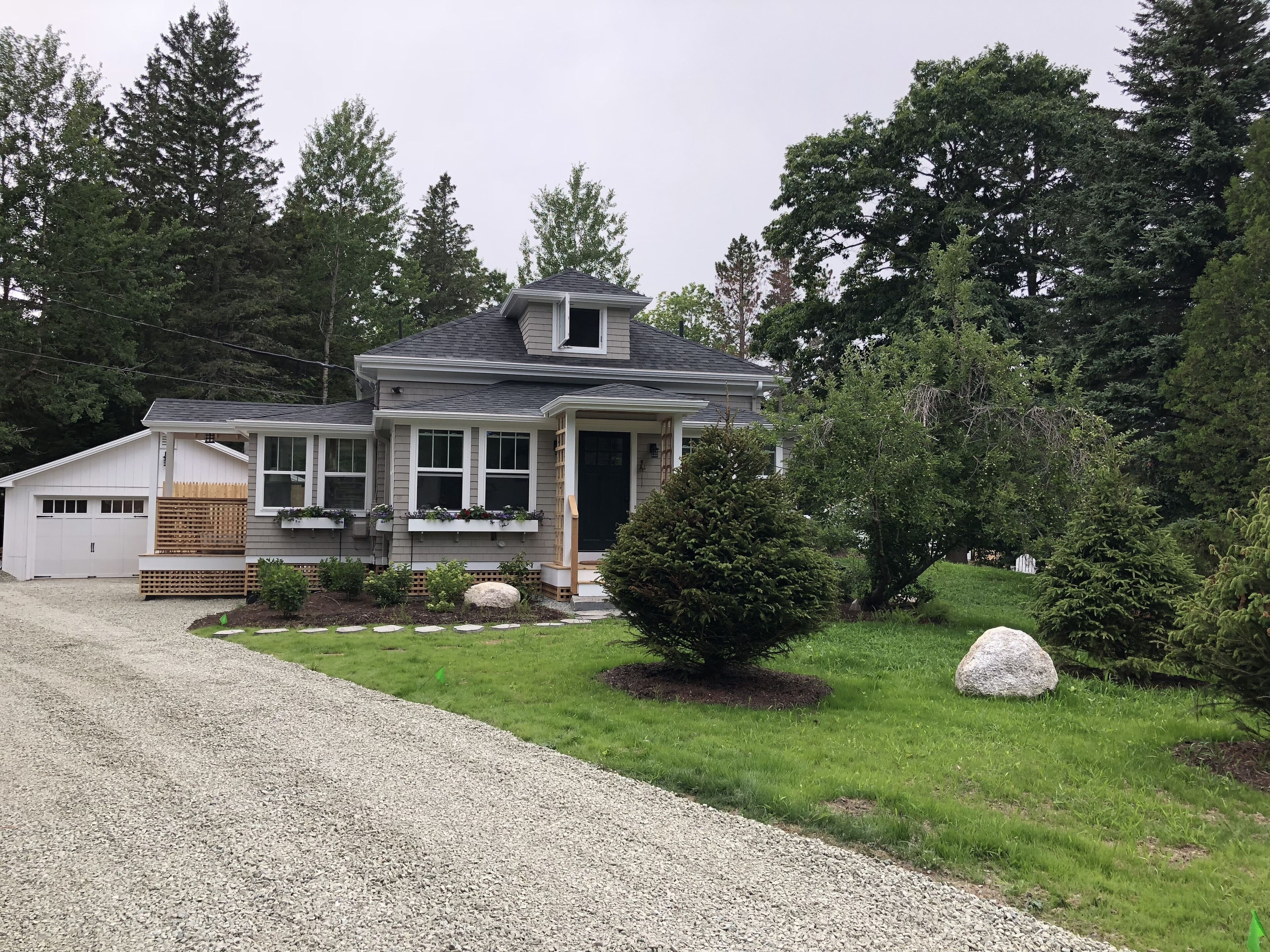 A two-story house with a garage, a covered porch, and a well-maintained lawn.