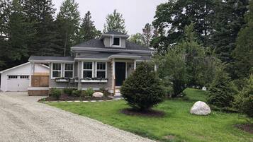 A two-story house with a garage, a covered porch, and a well-maintained lawn.