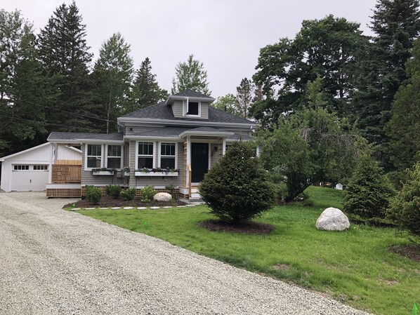 A two-story house with a garage, a covered porch, and a well-maintained lawn.