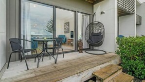 A modern outdoor seating area with a wooden deck, a hanging chair, and a table with chairs.