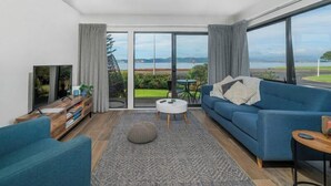 A modern living room with a blue sofa, a round coffee table, and a TV on a wooden stand.