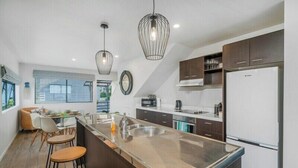 A modern kitchen with a central island, stainless steel appliances, and pendant lighting.