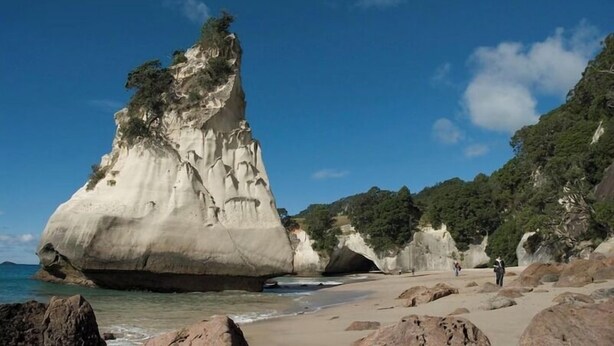 A coastal landscape with a prominent rock formation and a beach.