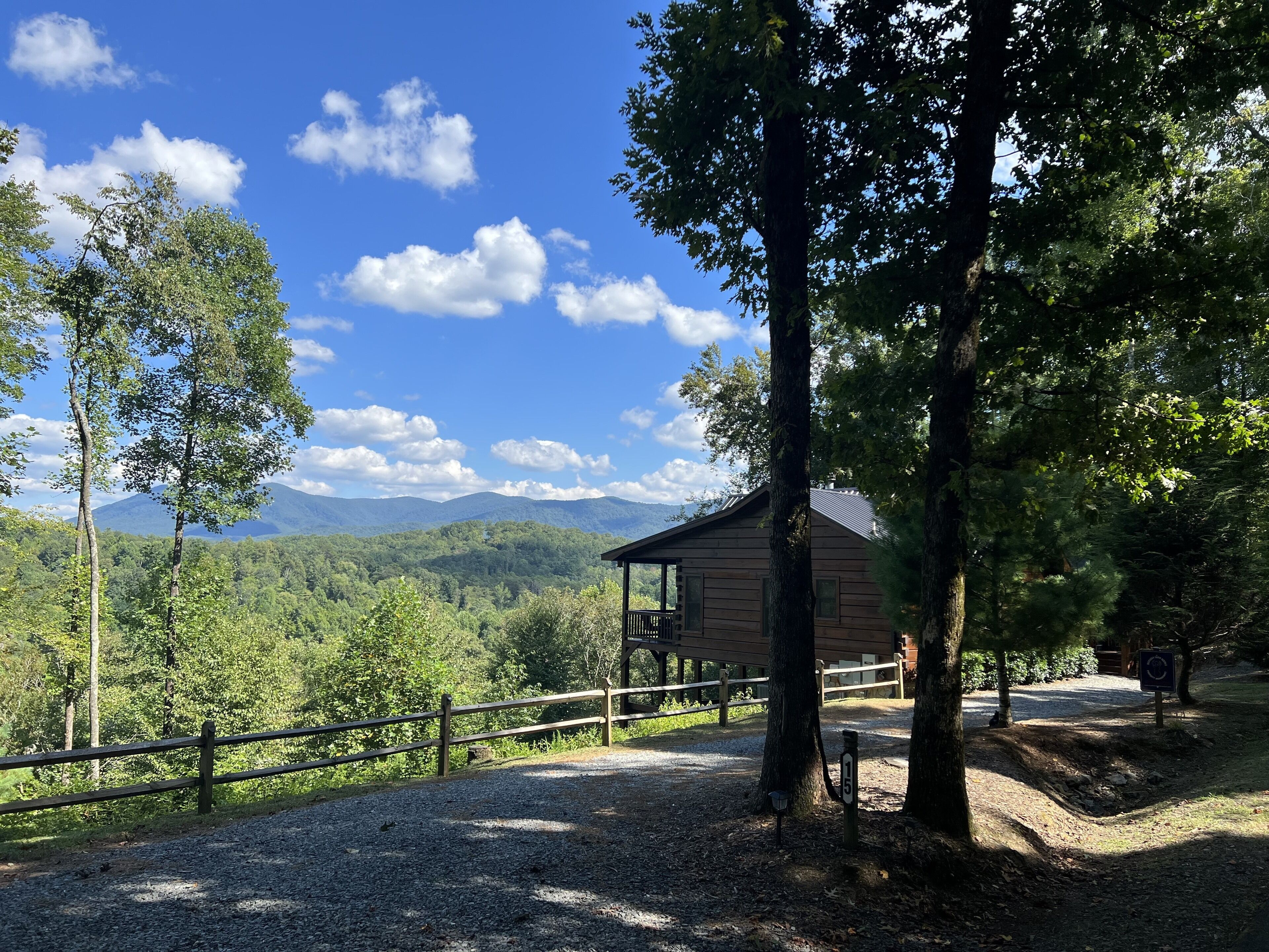 A cabin with a wooden exterior, surrounded by trees and a gravel path.