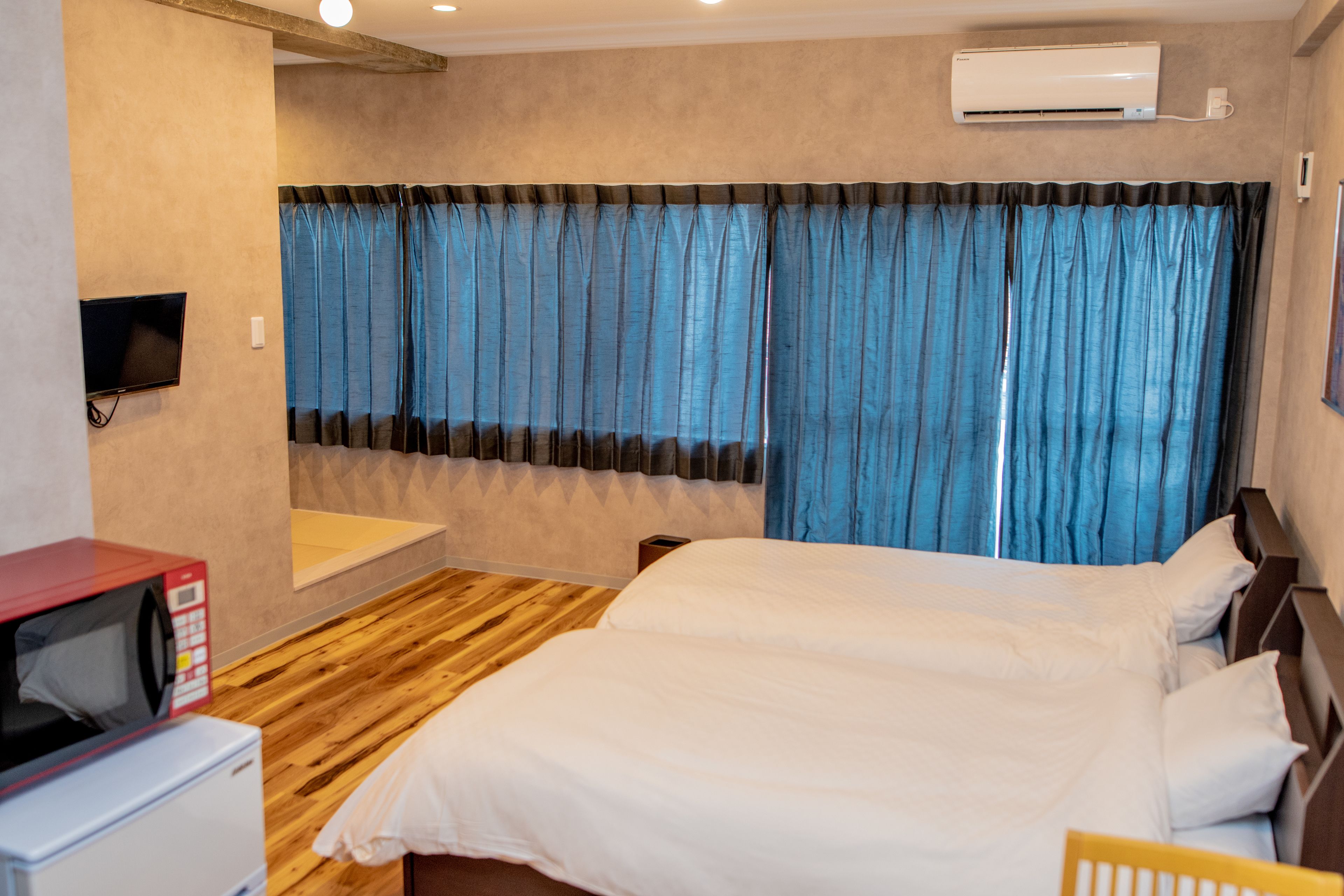 Ein Hotelzimmer mit Bett, Fernseher, Mikrowelle und Klimaanlage.