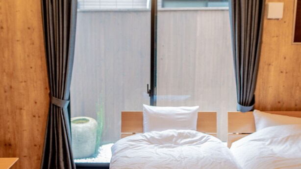 Een hotelkamer met een bed, twee nachtkastjes en een raam met gordijnen.