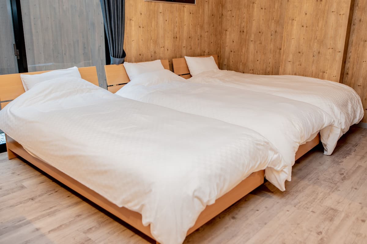 A double bed with a wooden frame and white bedding in a room with wooden panel walls and flooring.
