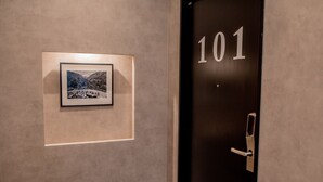 Een deur met het nummer 101, een lijst met een foto aan de muur en een deurklink.
