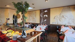 Un restaurante con bufé, mesas, sillas y un mural en la pared.