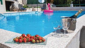 Ein Poolbereich mit einer Champagnerflasche, Gläsern und Erdbeeren auf einem Tisch.