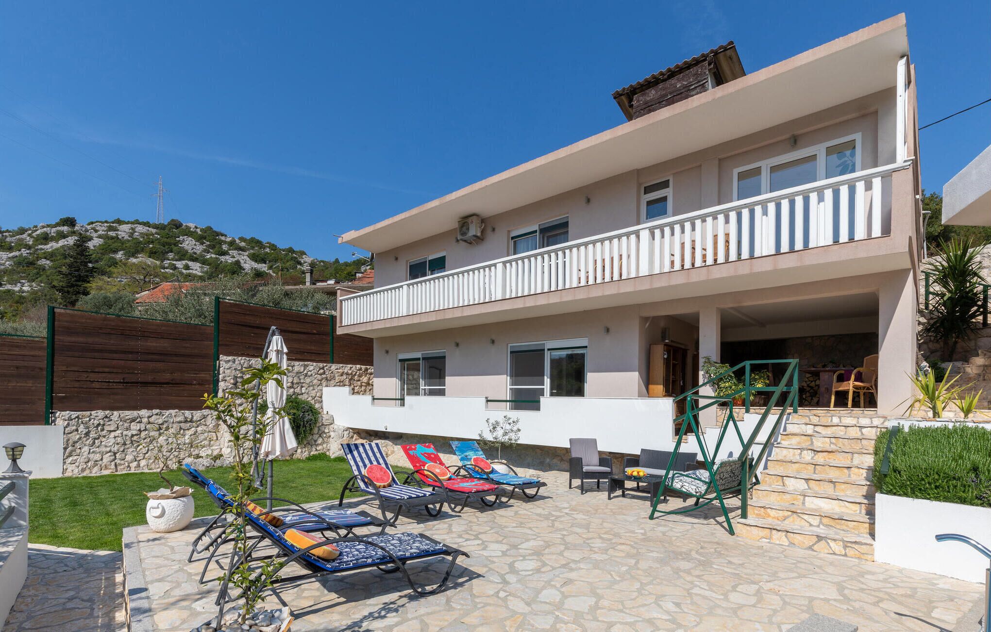 A two-story building with a balcony, stone flooring, and outdoor seating.