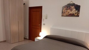 Una camera da letto con un letto, un armadio, una porta e un quadro appeso al muro.