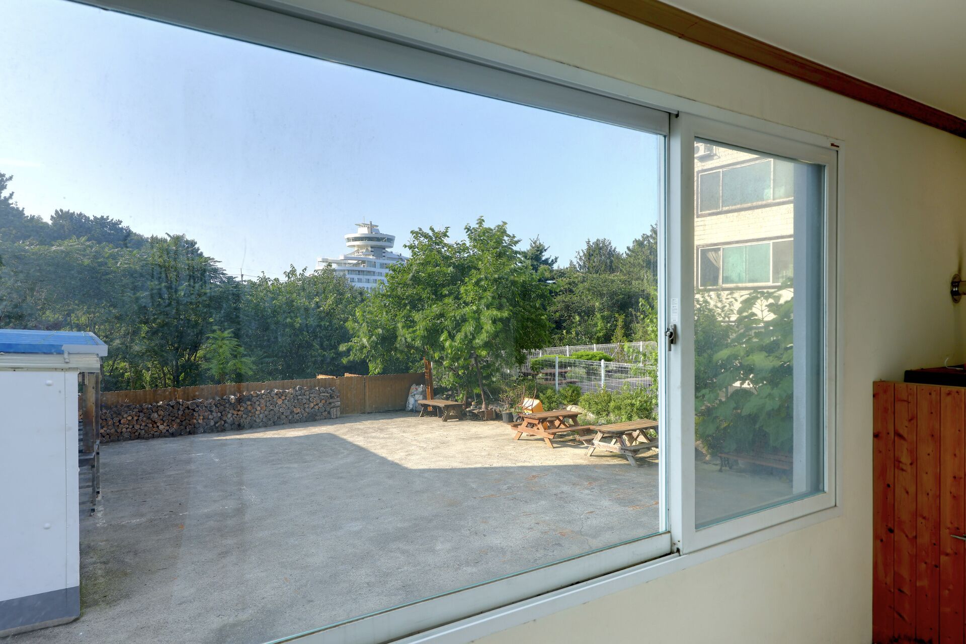 A room with a large sliding glass door leading to an outdoor area with a view of a pagoda and trees.