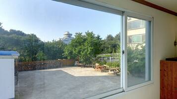 A room with a large sliding glass door leading to an outdoor area with a view of a pagoda and trees.