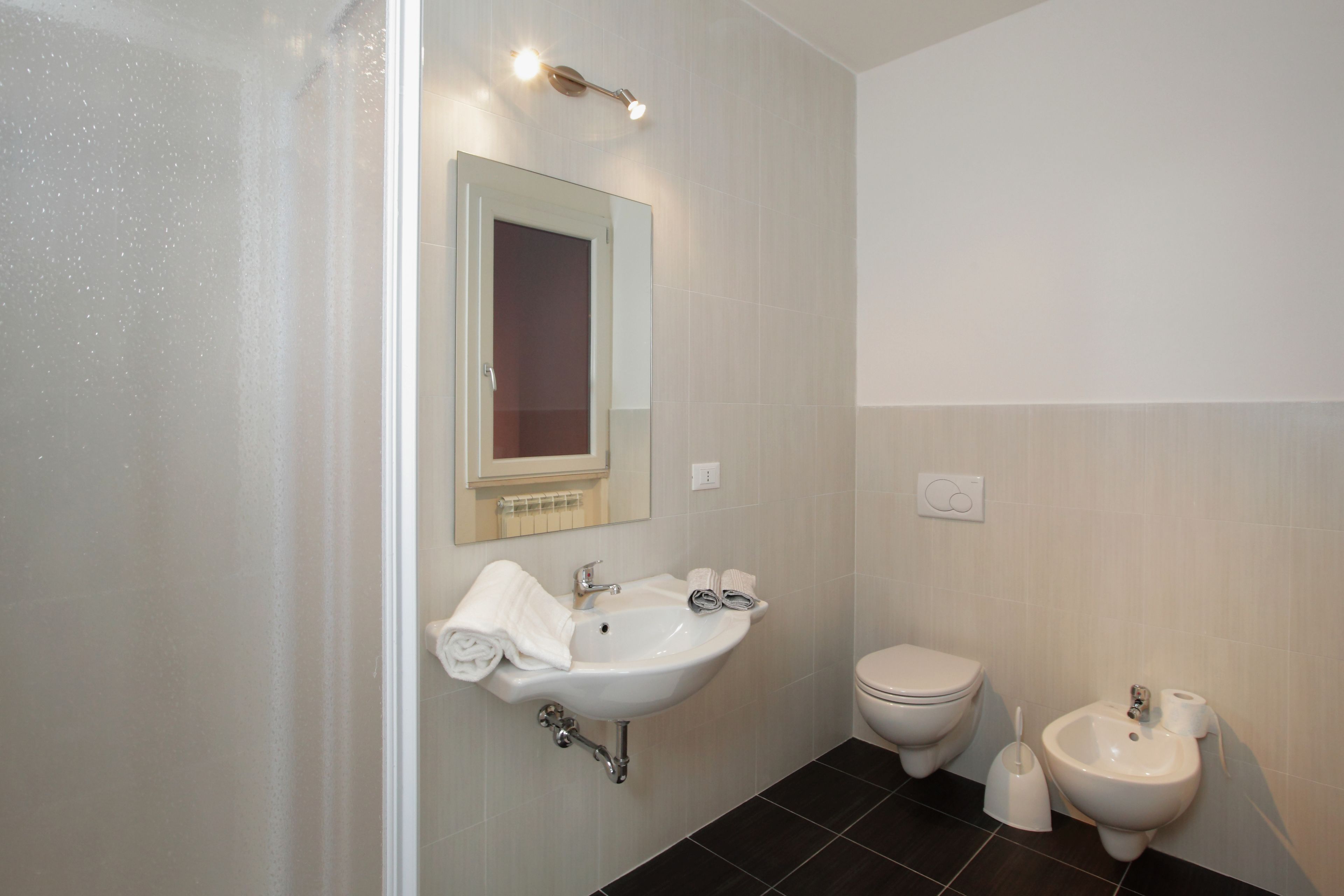 A bathroom with a sink, toilet, bidet, and a mirror.